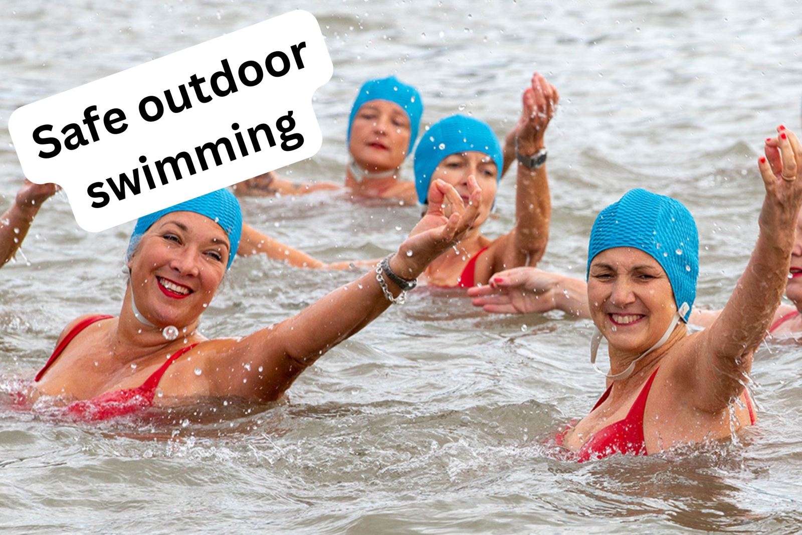 A group of synchro swimmers in red costumes and blue hats